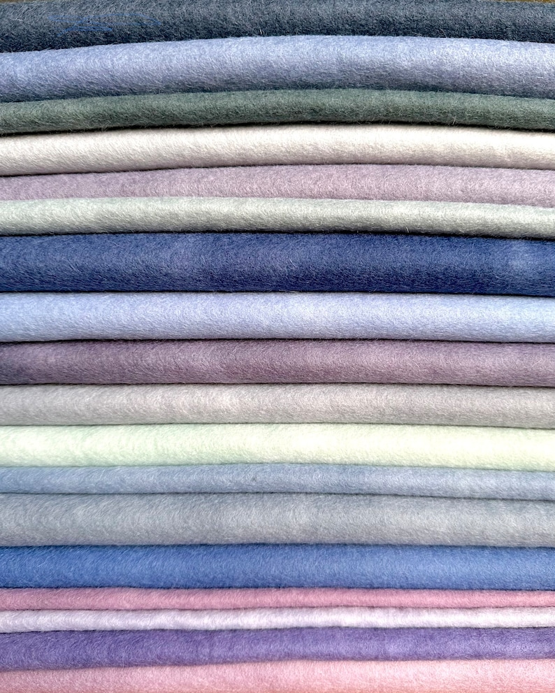 May include: A stack of 20 different colored felt fabric squares. The colors range from light to dark shades of blue, purple, pink, and gray.