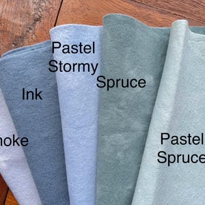 May include: Five fabric swatches in different shades of blue and green. The swatches are labeled "Smoke", "Ink", "Pastel Stormy", "Spruce", and "Pastel Spruce".