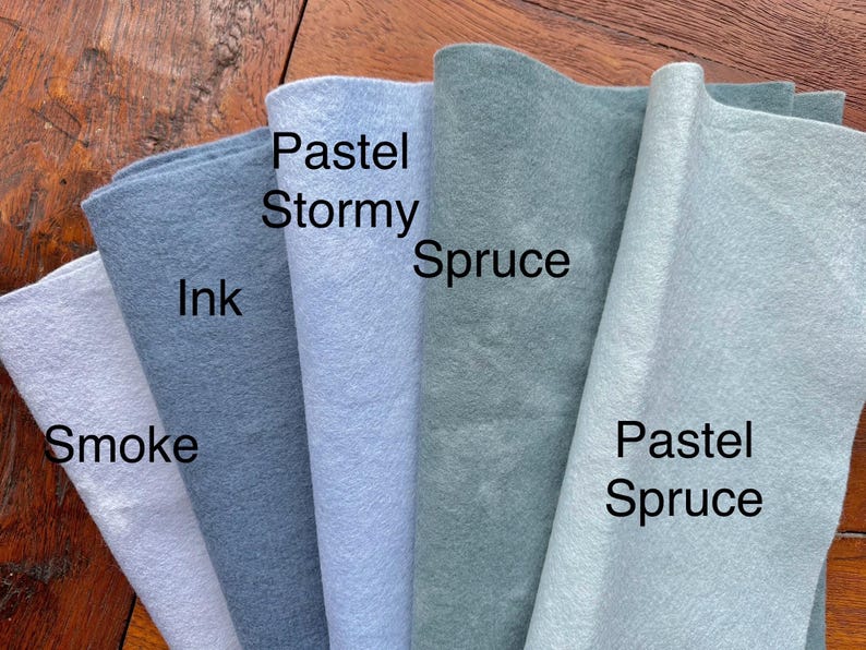 May include: Five fabric swatches in different shades of blue and green. The swatches are labeled "Smoke", "Ink", "Pastel Stormy", "Spruce", and "Pastel Spruce".
