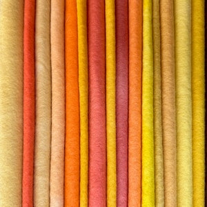 以下が含まれることがあります： 薄いベージュから濃いオレンジまで、20種類の異なる色のフェルト生地のコレクションです。フェルトはグラデーションパターンで配置されており、最も明るい色は一端、最も暗い色は反対側にあります。