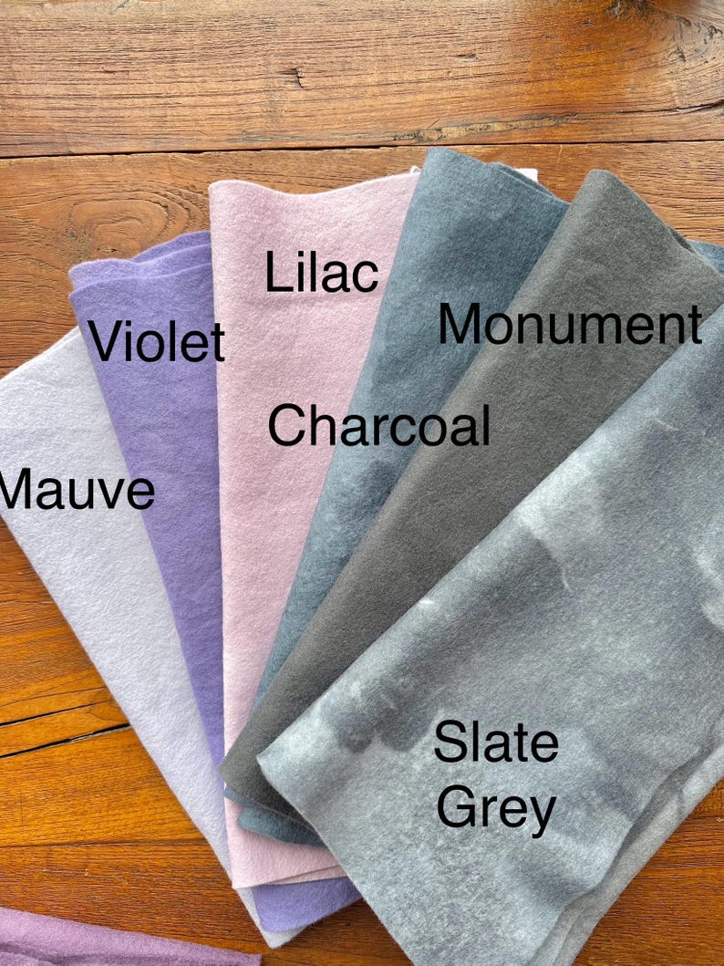 May include: A collection of six fabric swatches in various shades of purple, gray, and blue. The swatches are labeled "Mauve", "Violet", "Lilac", "Charcoal", "Monument", and "Slate Grey".