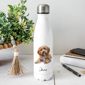 May include: White stainless steel water bottle with a watercolour illustration of a brown and tan dog. The dog's name, "Jane", is written in script below the image. The bottle has a silver cap.