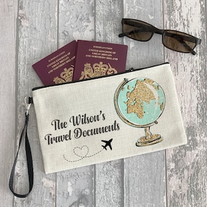 Könnte beinhalten: Eine beige Reise-Tasche aus Canvas mit einem schwarzen Reißverschluss und einem schwarzen Riemen. Die Tasche hat einen Globus mit goldenem Glitzer und ein Flugzeug mit einer herzförmigen Spur. Der Text "The Wilson's Travel Documents" ist auf der Tasche aufgedruckt.