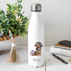 May include: White stainless steel water bottle featuring a watercolour illustration of a dachshund dog with the name "Sophia" printed at the bottom.