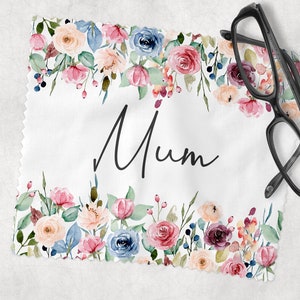 May include: A white microfiber cleaning cloth with a floral border in shades of pink, blue, and peach, with the word "Mum" in black script. Black eyeglasses rest on the cloth.