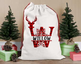 May include: White canvas gift bag with red and black buffalo check trim. The bag features a large red and black buffalo check letter "W" with a snowflake design and the name "WILLOW" written in black.