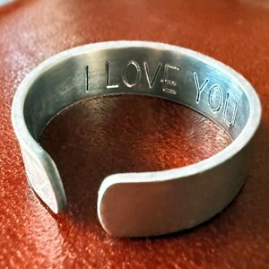 May include: A silver metal bracelet with the words "I love you" engraved on the inside.