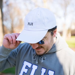 May include: A white baseball cap with the word "FIJI" embroidered in black on the front.