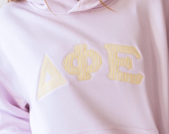 Sudadera con capucha de seersucker amarillo claro y curvado para chica, moderna, con letras griegas de hermandad, sudadera con capucha de color, sudadera con capucha con letras grandes y pequeñas.