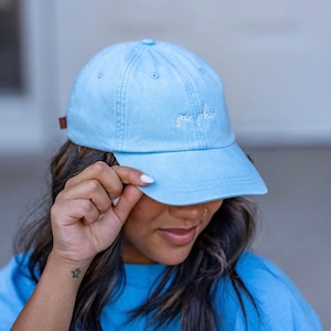 May include: A light blue baseball cap with white embroidery that reads "pi phi".