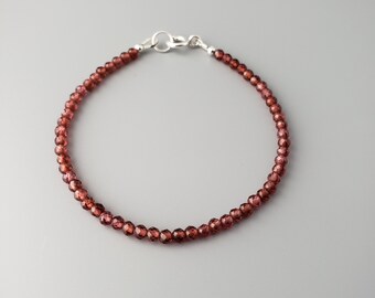May include: A delicate bracelet made with small, faceted garnet beads. The bracelet is secured with a silver clasp.