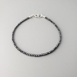 May include: A black beaded bracelet with a silver clasp.