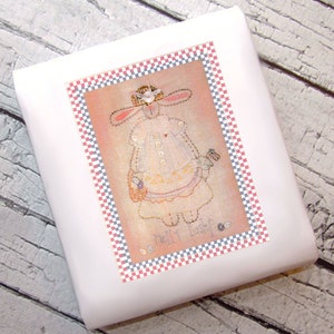 Op de afbeelding: Een witte stoffen tas met een roze-witte geruite rand. De tas heeft een vintage illustratie van een konijn met een hoed en een mandje met eieren. De tekst "Prettige Pasen" staat onder het konijn.
