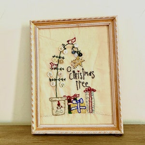 May include: A framed embroidery of a Christmas tree made with buttons and red birds. The tree is in a pot with a snowman. The text "Christmas tree" is embroidered below the tree.