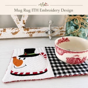 May include: A rectangular fabric mug rug featuring a quilted white snowman face with a black top hat, orange nose, and red and white striped trim. The right side of the mat has a black and white gingham pattern. A white bowl with red floral patterns sits on top.