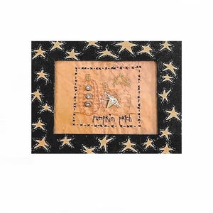 May include: A black framed clock with a gold star pattern. The clock face has a pumpkin patch design and the text "pumpkin patch".