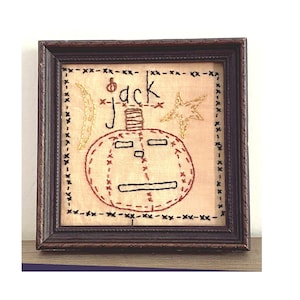 以下が含まれることがあります： ジャックという文字が書かれた、刺繍されたジャック・オー・ランタンの額縁入り作品です。