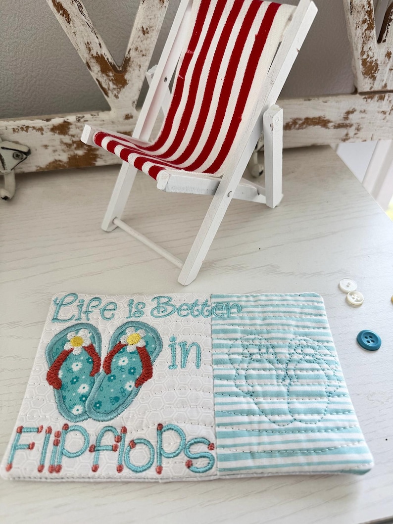 Pu&ograve; includere: Una sedia a sdraio in legno bianco in miniatura con tessuto a righe rosse e bianche. Un sottobicchiere decorativo trapuntato con la scritta "Life is Better in Flip Flops" e disegni di infradito ricamati.