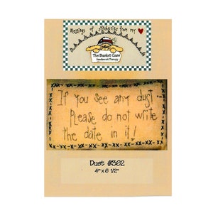 Op de afbeelding: Een ingelijst kunstwerk met de tekst "If you see any dust... Please do not write the date in it!" en "Dust #362". Het kunstwerk bevat ook een kleine afbeelding met de tekst "The Basket Case Needlework Therapy". Het kunstwerk meet ongeveer 10 cm x 16,5 cm.