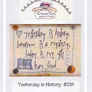 May include: A white background with a stitched quote that reads "Yesterday is history, tomorrow is a mystery, today is my gift from God." The quote is surrounded by a stitched border with buttons and a small piece of plaid fabric. The text "Yesterday is History #219" is at the bottom of the image.