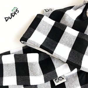 May include: Black and white checkered fabric with a white label that says "DUDIS" and a smaller white label with two smiling faces.