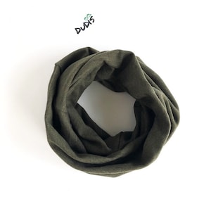 May include: A dark green infinity scarf made of soft fabric. The scarf is rolled up and appears to be made of a knit material.
