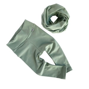 May include: A sage green pair of leggings and a matching infinity scarf. The leggings have a wide waistband and the scarf is made of a soft, stretchy fabric.