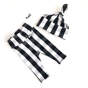 May include: Black and white checkered baby leggings and a matching knotted beanie. The leggings have a fold-over waistband and the beanie has a small tag with the word "Duds" on it.