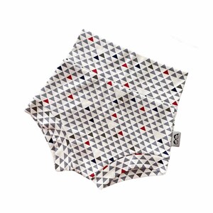 May include: White baby bloomers with a geometric pattern of red, blue, and gray triangles. The bloomers have a small tag with the text "OO" on the right side.