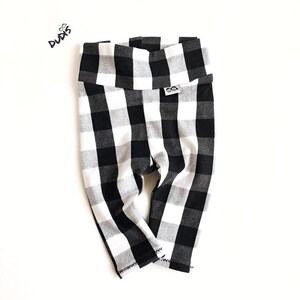 May include: Black and white checkered leggings for babies or toddlers. The leggings have a wide waistband and are made of a soft, stretchy fabric.