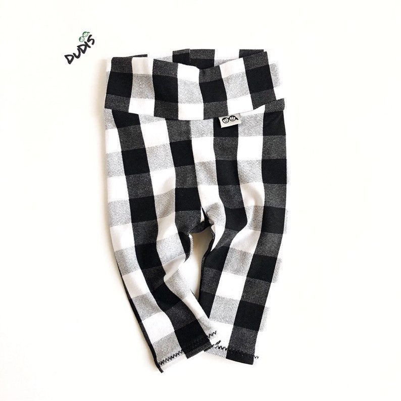 May include: Black and white checkered leggings for babies or toddlers. The leggings have a wide waistband and are made of a soft, stretchy fabric.