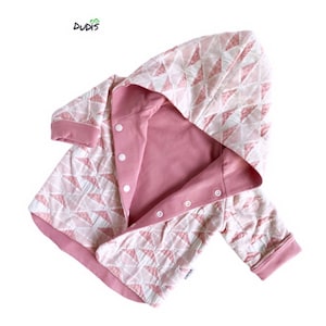 Puede incluir: Una chaqueta rosa y blanca con capucha y un patrón geométrico. La chaqueta tiene una cremallera y una capucha con cordón.