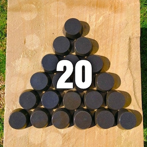 May include: A set of 20 black round discs arranged in a triangular pattern on a light brown surface.