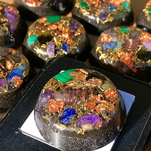 May include: A round, black, resin-based orb with a variety of crystals and copper wire embedded in it. The crystals include amethyst, lapis lazuli, green aventurine, and clear quartz. The orb is approximately 2 inches in diameter.