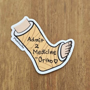 May include: A sticker featuring a cartoon illustration of a leg cast. The cast is tan with brown lines, and the foot is visible at the end. Text on the cast reads "Admit 2 Medicine - Ortho". The sticker has a white border and the text "MedQuirks".