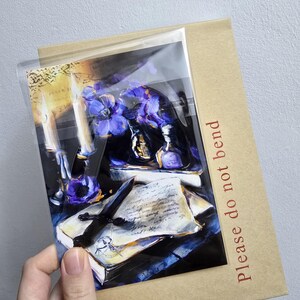 May include: A print of a still life scene featuring a candle, flowers, and a dagger on a book. The print is in a clear plastic sleeve and a brown cardboard backing with the text "Please do not bend" in red.