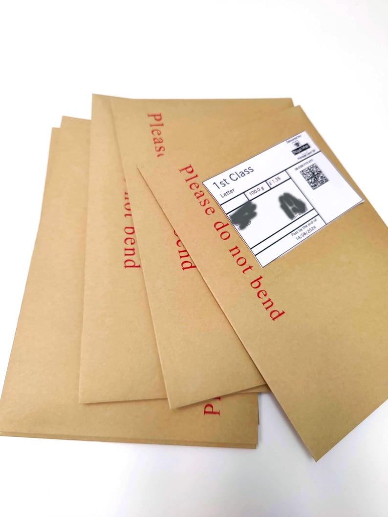 May include: A stack of brown paper envelopes with the words "Please do not bend" printed in red. One envelope has a white shipping label with a barcode and text. The envelopes are on a white background.