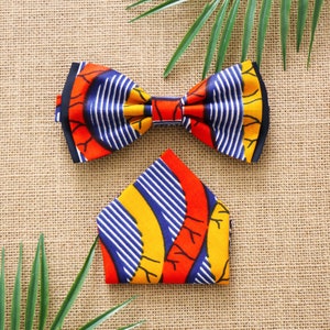 May include: A bow tie and pocket square with a colourful geometric pattern in shades of blue, yellow, orange, and red. The fabric has a woven texture.