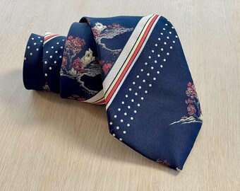 May include: A navy blue tie with a white polka dot pattern and a white, red, and yellow stripe. The tie also features a printed design of a landscape with trees and buildings.