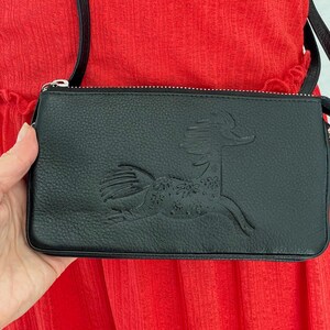 Pode incluir: Bolsa de ombro de couro preto com z&iacute;per prateado e um design de cavalo em relevo detalhado na frente.