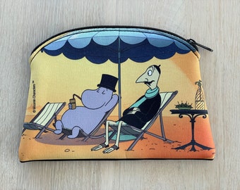 May include: A zippered pouch featuring a beach scene with two cartoon characters relaxing under a blue umbrella. One character is drinking from a straw, and the other is sitting in a chair. The pouch has a black zipper and trim.