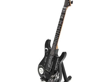 May include: Black electric guitar with a skull and moon design. The guitar has a black body and a black headstock. The guitar is on a black stand.