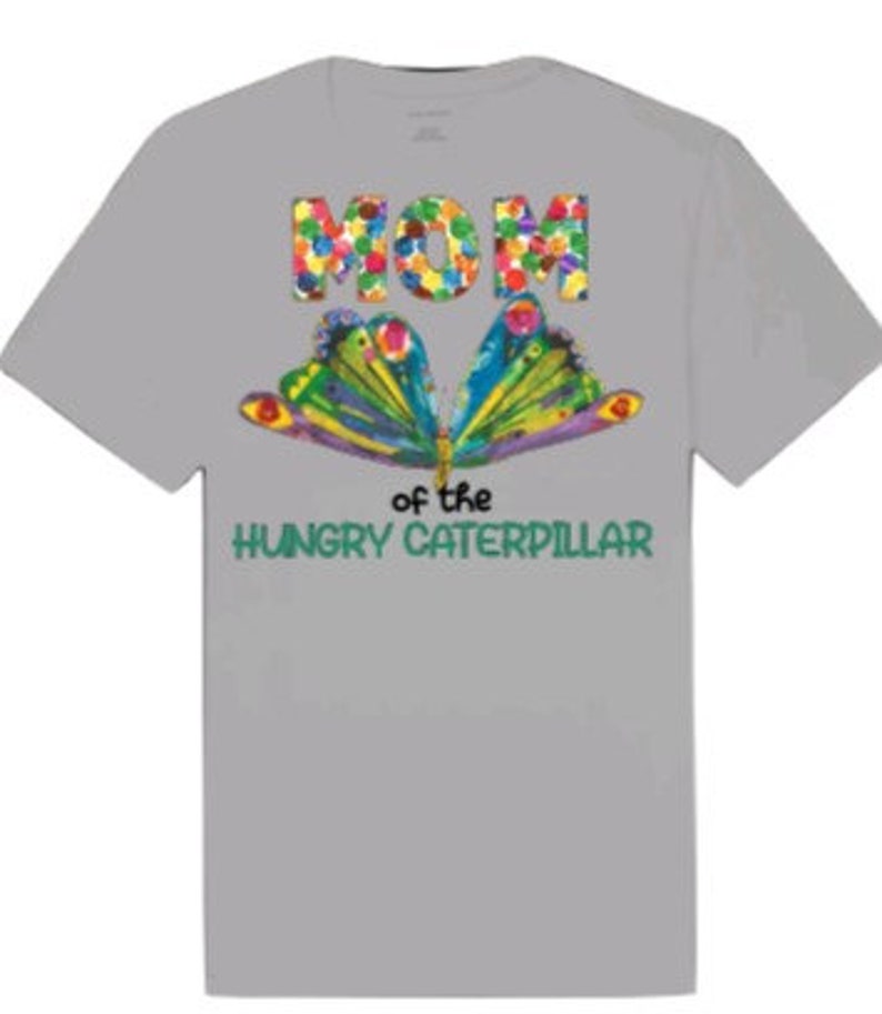 Puede incluir: Camiseta gris con una mariposa colorida y el texto "Mam&aacute; de la oruga hambrienta" impreso en ella.
