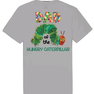 Puede incluir: Camiseta gris con un gr&aacute;fico colorido de "DAD" y una oruga verde con el texto "of the HUNGRY CATERPILLAR" debajo.