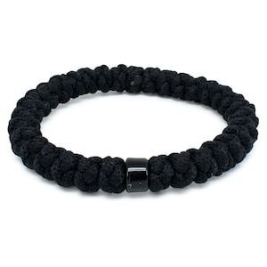 Könnte beinhalten: Ein schwarzes geflochtenes Armband mit einem schwarzen Perlenakzent.