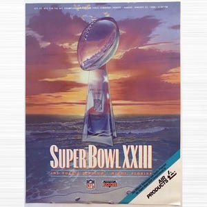 May include: A vintage Super Bowl XXIII poster featuring the Vince Lombardi Trophy, a football-shaped trophy, set against a sunset over the ocean. The poster includes the text "SUPER BOWL XXIII" and "JOE ROBBIE STADIUM, MIAMI, FLORIDA".