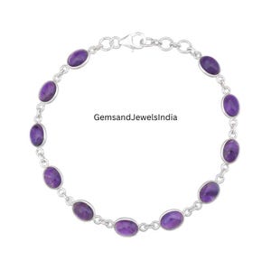 Puede incluir: Un brazalete de plata con piedras preciosas ovaladas de color púrpura. Las piedras están espaciadas a lo largo de la cadena. El brazalete tiene un cierre. El texto "GemsandJewelsIndia" es visible.