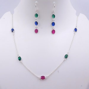 May include: A silver necklace and earrings set with green, blue, and red oval-shaped gemstones.