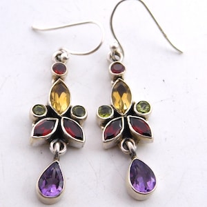 May include: A pair of silver dangle earrings with a floral design. The earrings feature a variety of gemstones, including amethyst, garnet, citrine, and peridot.