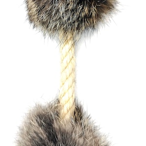 Könnte beinhalten: Ein Katzenspielzeug mit zwei flauschigen, braunen und grauen Fellbällen, die durch ein beiges Seil verbunden sind. Die Fellbälle haben ein dichtes, strukturiertes Aussehen, und das Seil ist fest verdreht.
